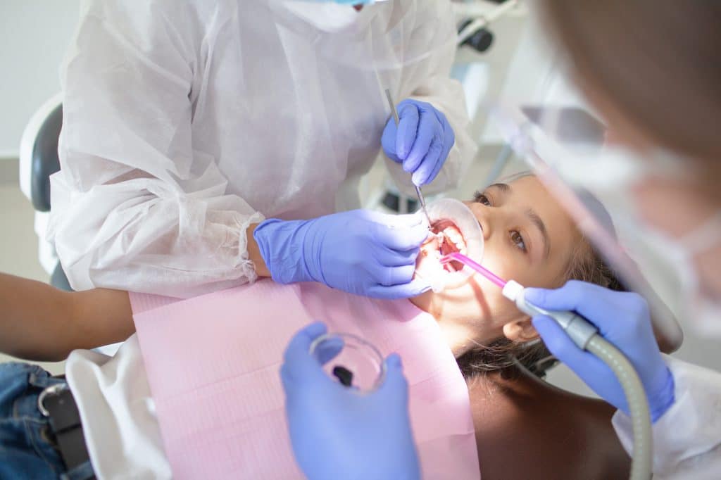 The dental surgeon makes the oral examination of mouth to female child in the dental office